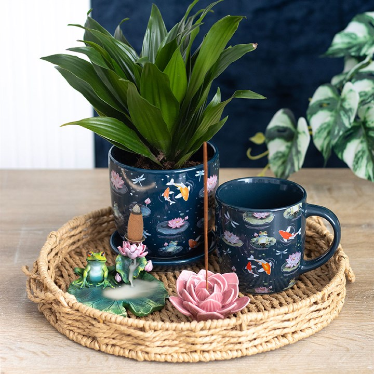 Navy blue mug with floral design and decorative items on a woven tray.