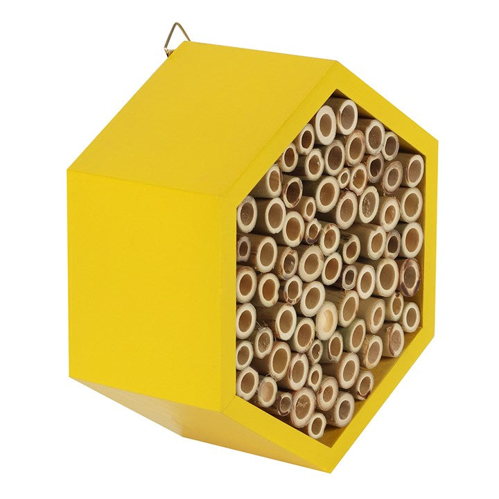 Yellow hexagonal bee house with wooden tubes inside on a white background