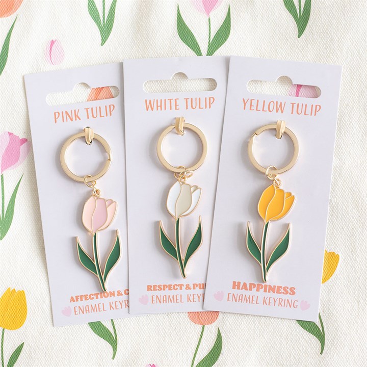 Three keychains with pink, white, and yellow tulips on their packaging against a floral background.