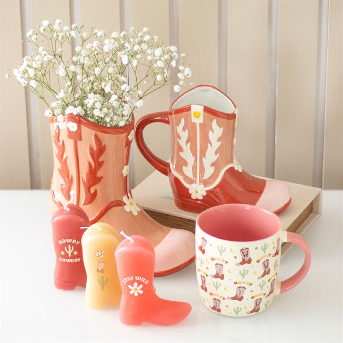 Decorative items including a boot-shaped mug, candle, and vase on a table.