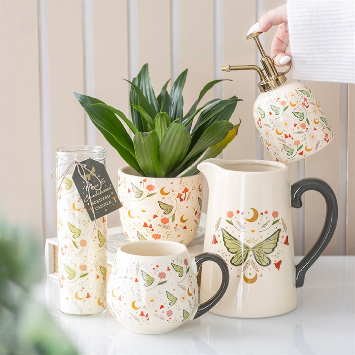 Decorative ceramic pitcher, mug, and jar with butterfly design on a neutral background