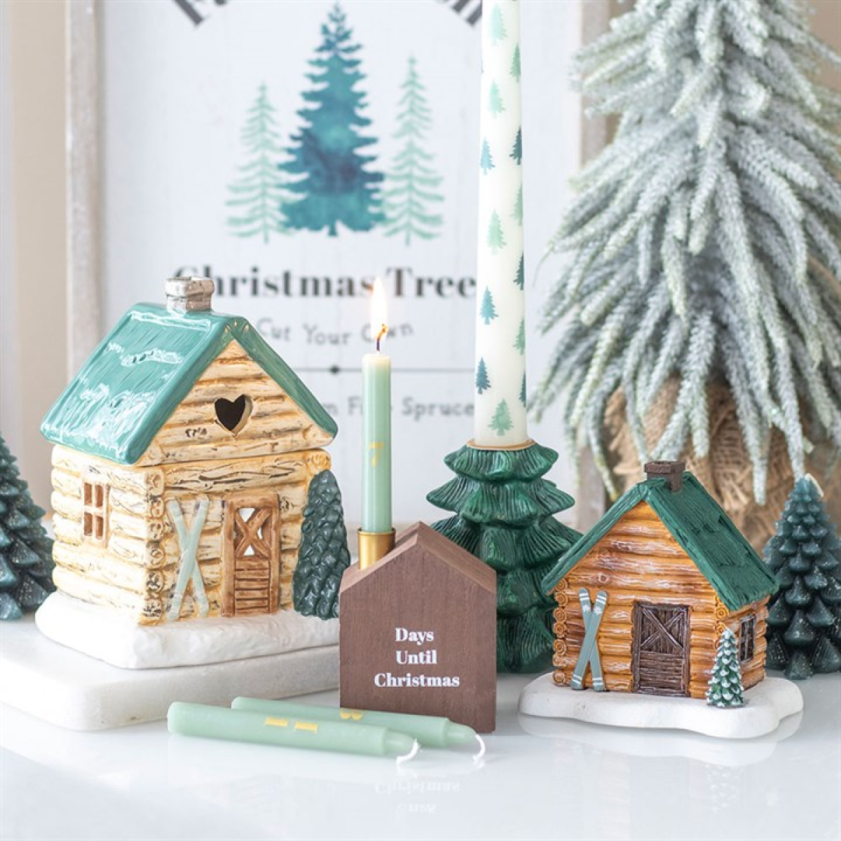 Decorative Christmas scene with log cabin figures, candles, and a 'Days Until Christmas' marker.