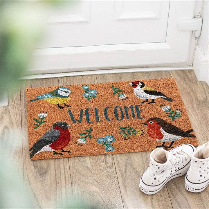 Decorative doormat with bird designs and the word 'Welcome' on a wooden floor.