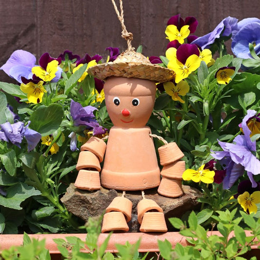 Terracotta plant pot man decoration among colorful flowers