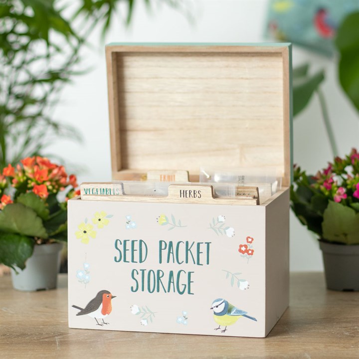 Seed packet storage box with illustrations of birds and plants on a wooden surface.