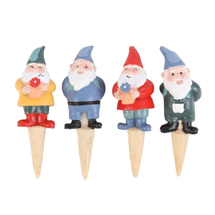 Four garden gnome figurines on wooden stakes with colorful clothing and accessories.