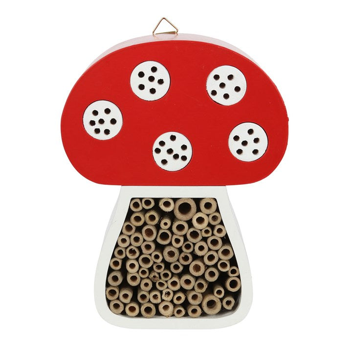 Mushroom-shaped insect hotel with red cap and white spots on a white background