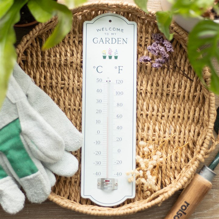 Gardening thermometer on a woven basket with gardening gloves and tools