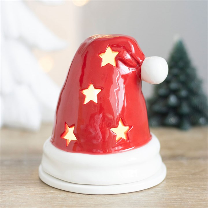 Red ceramic Santa hat with white stars on a wooden surface, blurred Christmas tree in the background