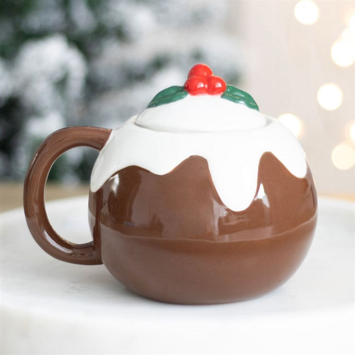 Mug shaped like a Christmas pudding with a holly on top, set against a blurred festive background.
