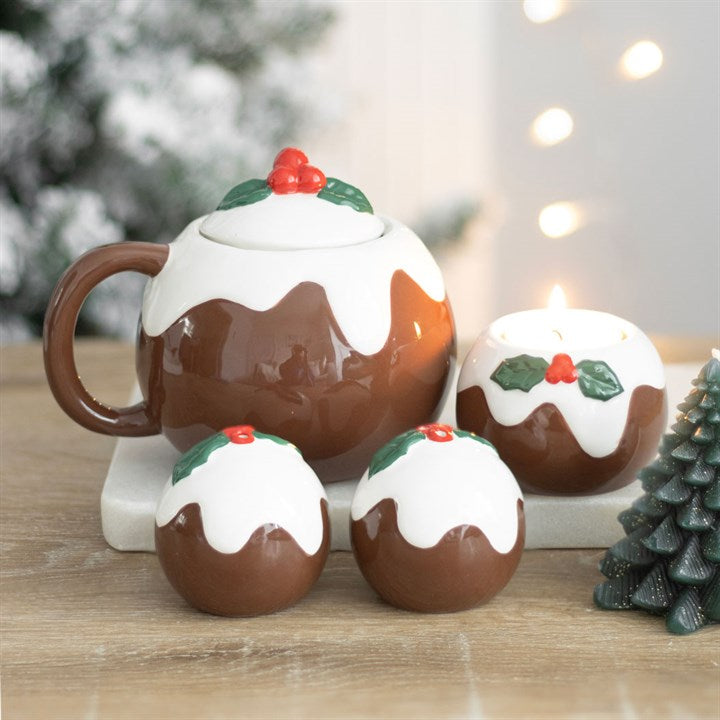 Christmas pudding-themed mugs and decorative items on a wooden surface with a blurred festive background.