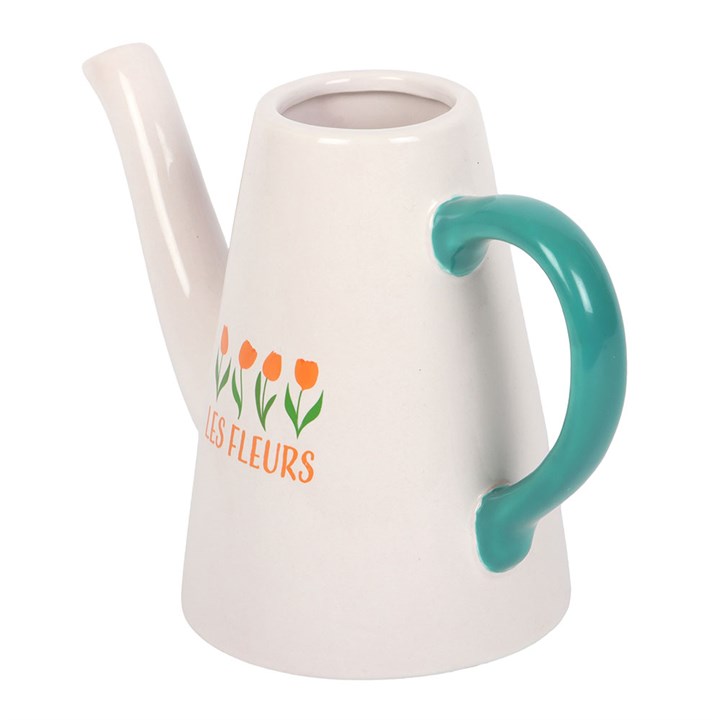 White ceramic watering can with green handle and floral design on a white background