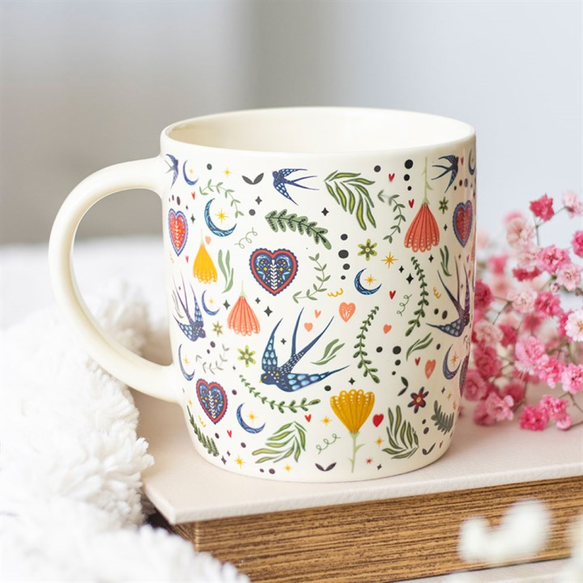 Decorative mug with colorful patterns on a surface with flowers in the background