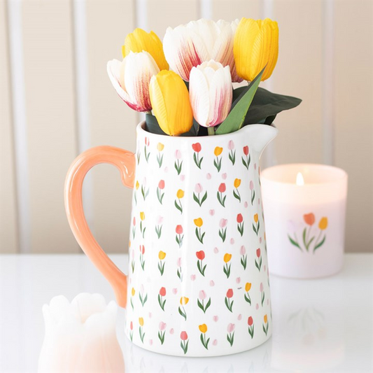 White jug with floral pattern filled with tulips on a white surface.