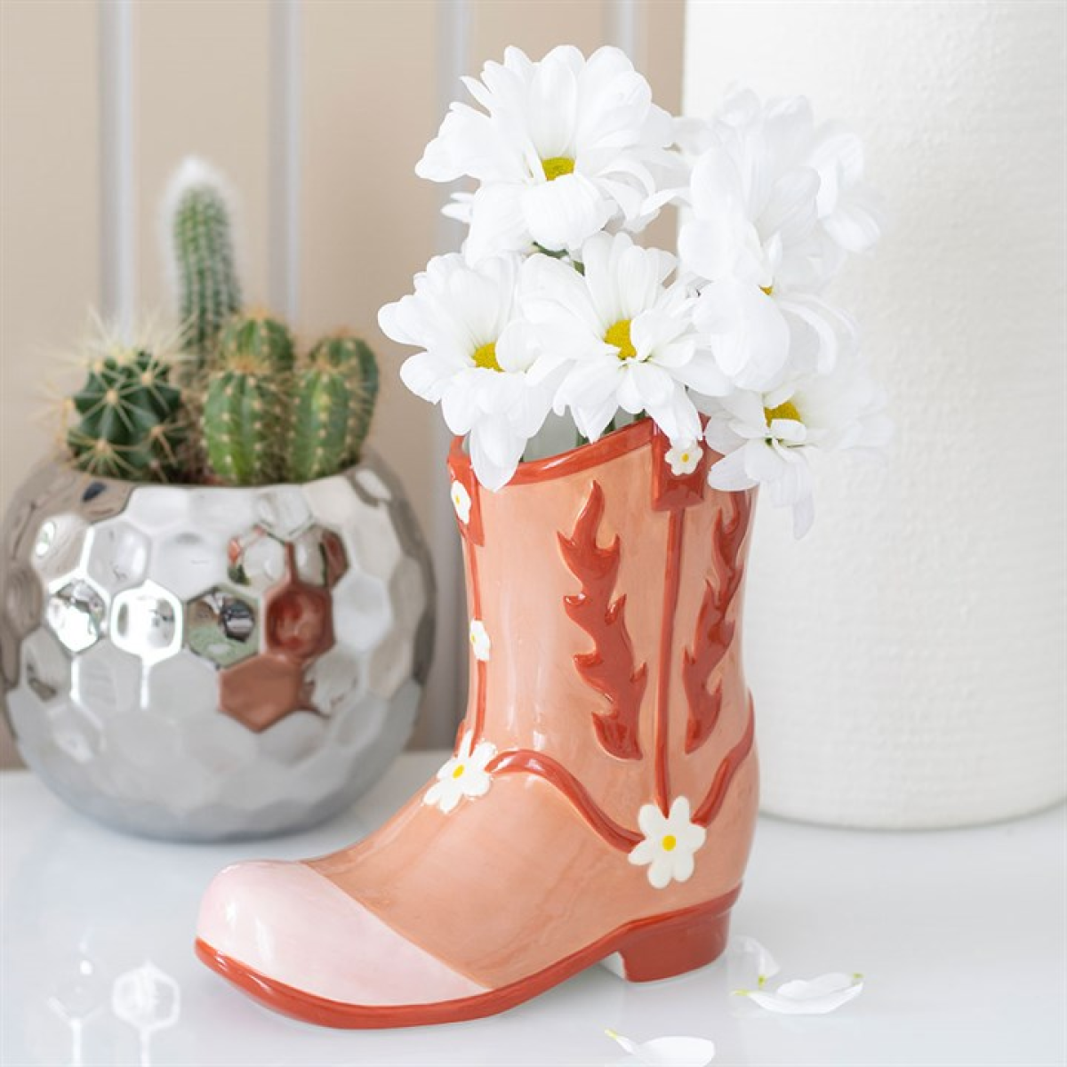 Ceramic boot with white flowers and a cactus plant in the background