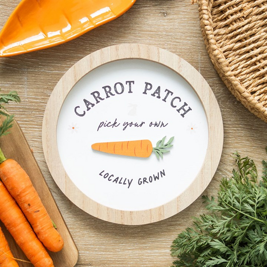 Round sign with 'Carrot Patch' text and carrots on a wooden surface