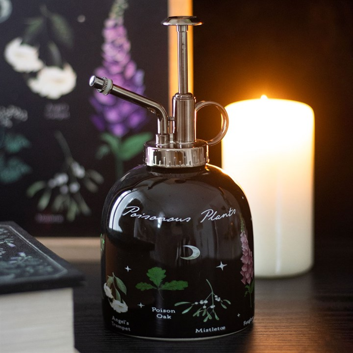 Black decorative bottle with floral designs on a table with a candle in the background