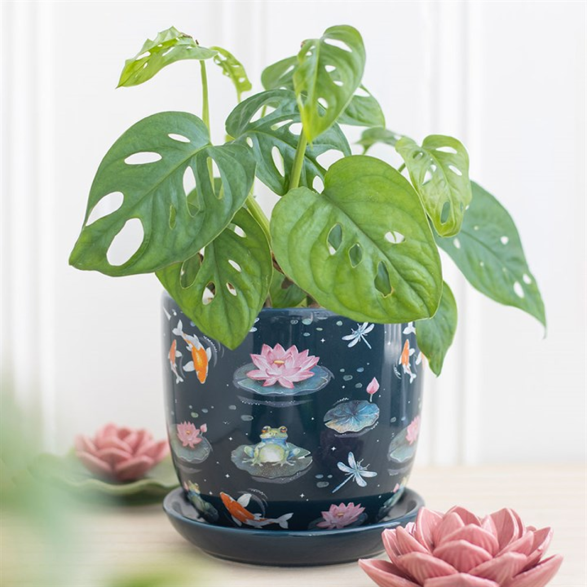Potted plant with decorative pot featuring nature-themed design on a light background