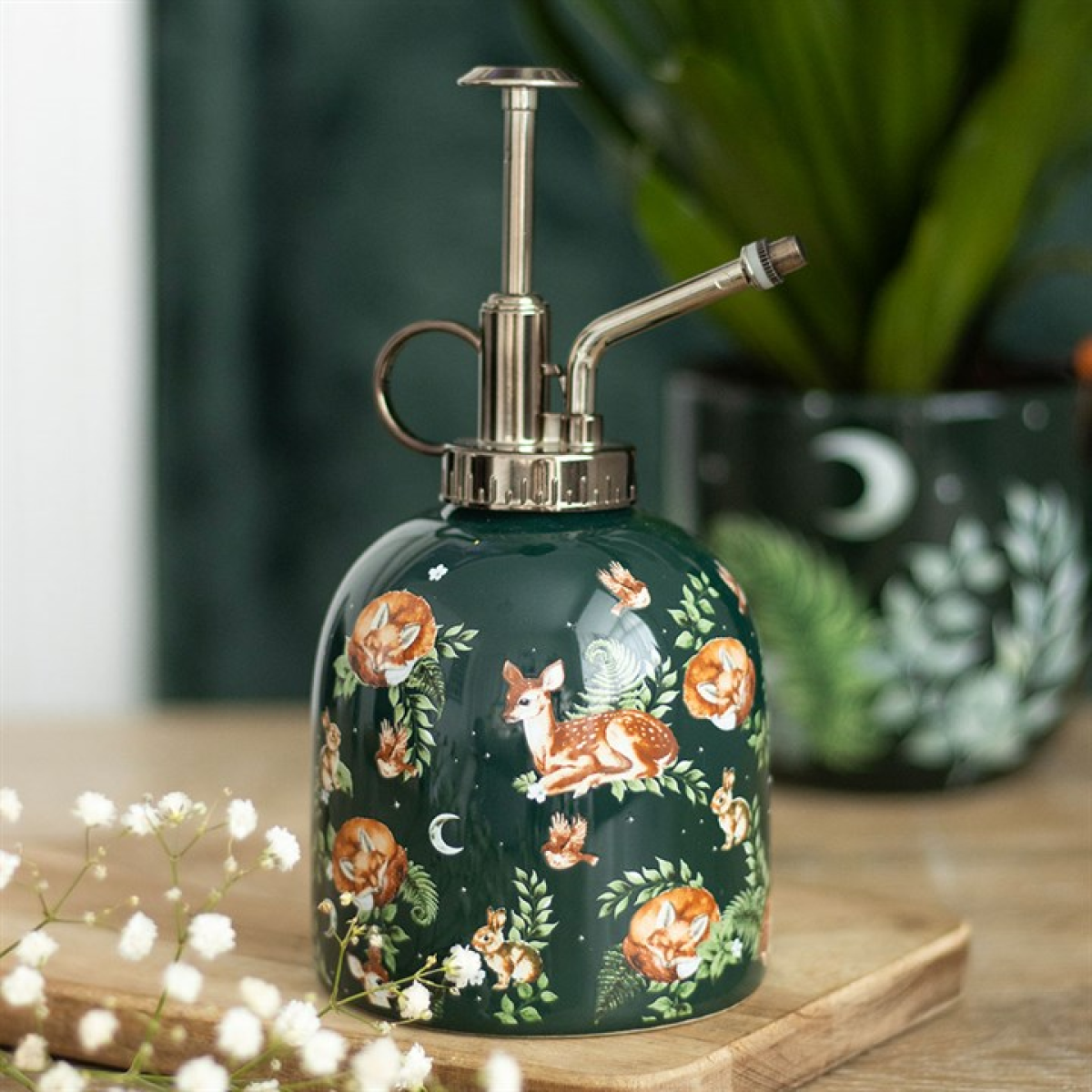 Decorative green bottle mister with animal and floral design on a wooden surface.