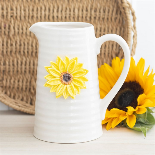 White ceramic pitcher vase with sunflower design on a wooden surface