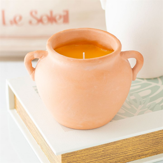 Terracotta-colored candle in a pot on a white surface with 'U & Soleil' branding in the background.